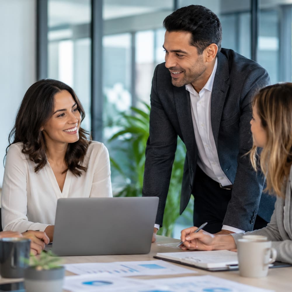 Small business owners collaborating around a laptop in a professional office, representing business owner’s policy insurance.