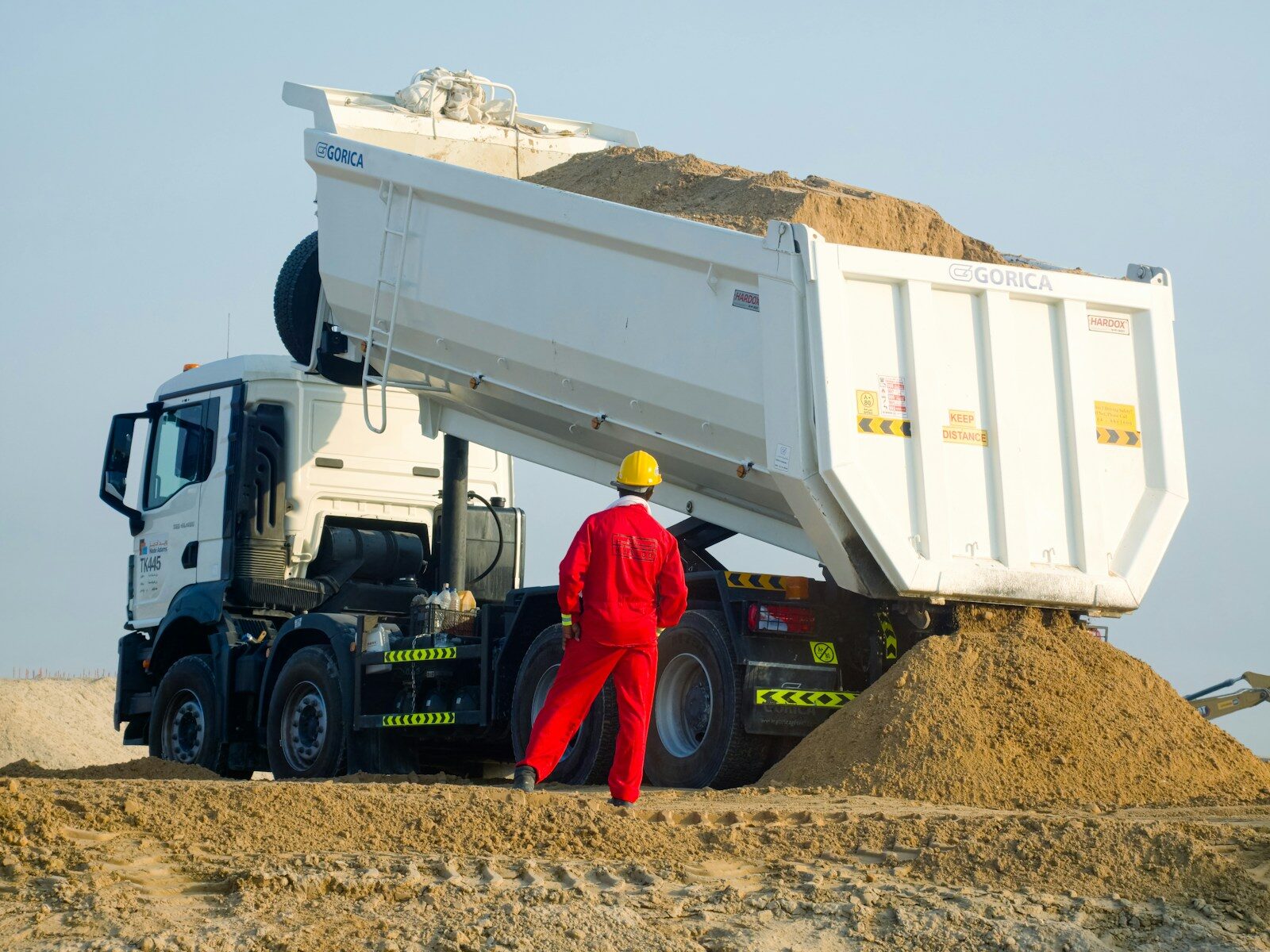 Dump Truck Insurance for Sand Dirt and Gravel Hauling Dump truck unloading sand at a worksite.